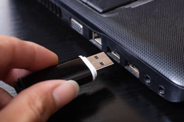 Elinde siyah USB bellek kartı ve dizüstü bilgisayarı kapat