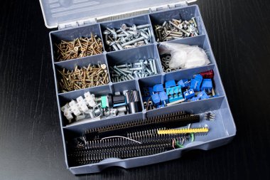 Tahta masadaki plastik bir kutuda çeşitli vidalar. Yakın plan.
