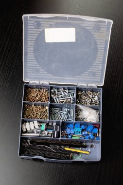 Tahta masadaki plastik bir kutuda çeşitli vidalar. Yakın plan.