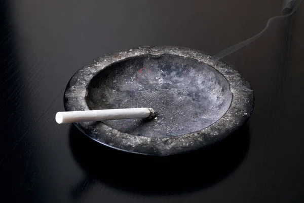 Eine brennende Zigarette und ein Aschenbecher in Großaufnahme — Stockfoto