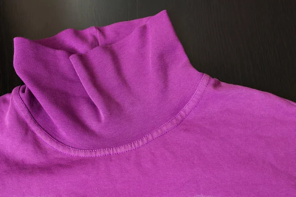 Part of pink sweater on wooden background close up