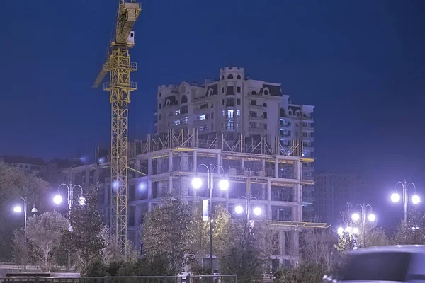 Lightening multi-storey buildings under construction and cranes at night.