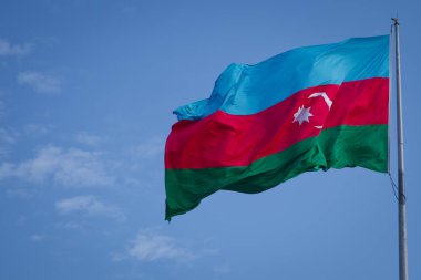 Mavi gökyüzünün arka planında Azerbaycan 'ın ulusal bayrağı. Azerbaycan bayrağı gökyüzüne karşı rüzgarda dalgalanıyor