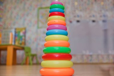 Eğitici oyuncaklar izole sarı halkalar, sürükleyici küçük bebekler için. Yığılmış dairesel bloklar renkli piramidi. Piramit kurmak--dan izole sarı arka plan üzerinde renkli plastik halkalar.