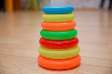 Yığılmış dairesel bloklar renkli piramidi. Piramit kurmak--dan izole sarı arka plan üzerinde renkli plastik halkalar.