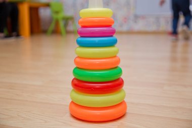 Yığılmış dairesel bloklar renkli piramidi. Piramit kurmak--dan izole sarı arka plan üzerinde renkli plastik halkalar.