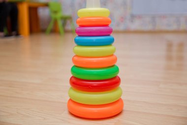 Yığılmış dairesel bloklar renkli piramidi. Piramit kurmak--dan izole sarı arka plan üzerinde renkli plastik halkalar.