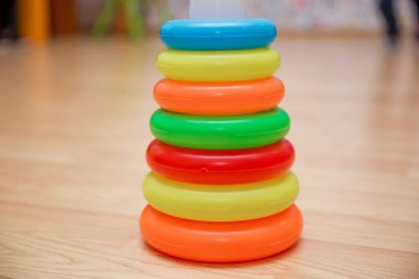 Yığılmış dairesel bloklar renkli piramidi. Piramit kurmak--dan izole sarı arka plan üzerinde renkli plastik halkalar.