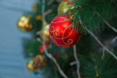 Kırmızı ve altın top bir saatin arka planında asılı. Yeni bir yılın zamanı geldi. Çok renkli parlama ve parlaklık. Altın kutu