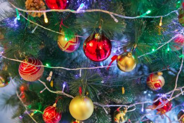 Kırmızı ve altın top bir saatin arka planında asılı. Yeni bir yılın zamanı geldi. Çok renkli parlama ve parlaklık. Altın kutu