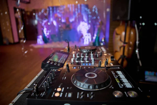 closeup hands of DJ at the control panel wearing in white shirt. disc jockey playing on the professional equipment at night club. concept of clubbing lifestyle