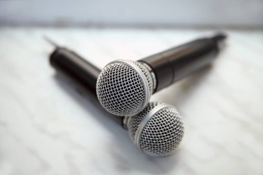 Beyaz arka planda izole edilmiş iki gümüş mikrofon. Konferans masasında iki kablosuz mikrofon var..
