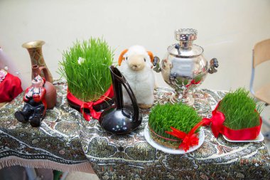 Novruz tatil arka plan. Bir kırmızı kurdele yeşil semeni ile bağlı. Semaver. Koyun kukla