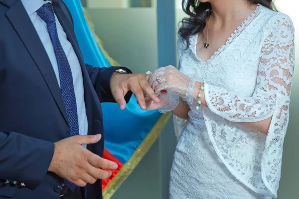 Свадьба. Девушка в белом платье и парень в костюме. Жених надевает кольцо на невесту. Процесс бракосочетания и обмена кольцами . — стоковое фото