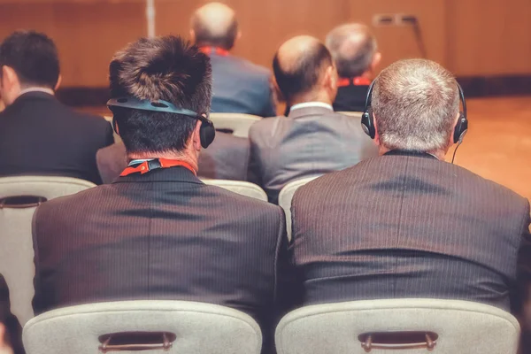 Unrecognizable conference people using headphones for translation during event. men listen to the translation of the headphones in the convent