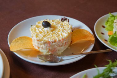 Stüdyo Fotoğraf . Beyaz bir tabak, seçici odak üzerinde kızarmış patates pasta ile Salata . Patates mayonez salatası . Yakın çekimde bir aperatif için tuzlu cips . Balık, havuç ve yumurta ile porsiyon katmanlı salata.