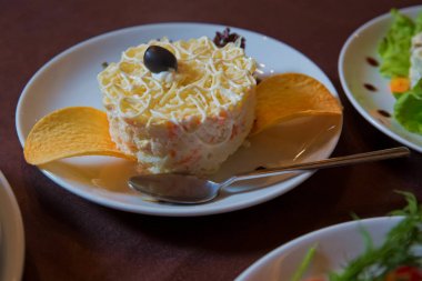 Stüdyo Fotoğraf . Beyaz bir tabak, seçici odak üzerinde kızarmış patates pasta ile Salata . Patates mayonez salatası . Yakın çekimde bir aperatif için tuzlu cips . Balık, havuç ve yumurta ile porsiyon katmanlı salata.