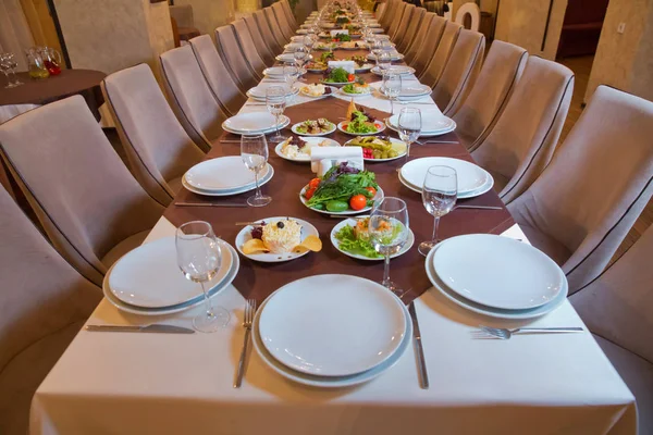 Servicio de vajilla con vajilla y cristal en el restaurante antes de la fiesta. Sirve mesa de fiesta, cubiertos, vajilla, vasos, plato, tenedor. Ensaladas y encías. Comida en la mesa en el restaurante  . — Foto de Stock