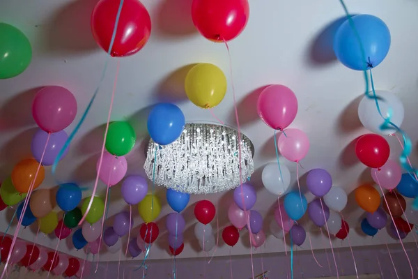 Globos de colores flotan en el techo blanco de la habitación para la fiesta. Boda o niños cumpleaños fiesta decoración interior. Globos de helio. lámpara de araña. candelabro — Foto de Stock