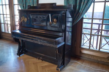 Eski ahşap siyah piyano. Siyah piyano duvara karşı duruyor. Ön görünümde ahşap müzik aleti eski ahşap siyah piyano tuşları .