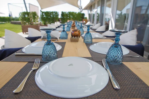 Comedor de lujo con mesa de madera en el hogar. Ajuste de mesa en el restaurante. Elegante mesa configurada para la recepción de cumpleaños o cena de banquete al aire libre. Placa, tenedor, cuchara. Mesa configurada para comedor . — Foto de Stock