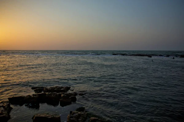 Красивий захід сонця на пляжі, дивовижні кольори, світловий промінь світить через хмарність. Азербайджанський море і пляж. Йде звук морських хвиль. Рибалка риб в море . — стокове фото