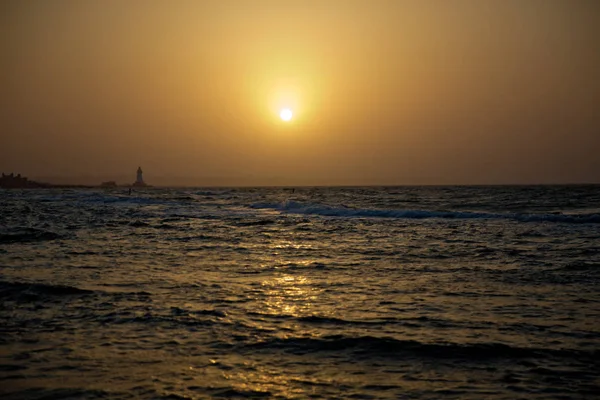 Закат на пляже, удивительные цвета, свет, сияющий сквозь облака. Азербайджан море и пляж. Звук морских волн приближается. Рыбак рыбачит в море  . — стоковое фото