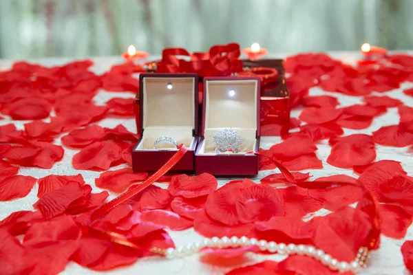 Šperky, návrh a romantické pojetí - diamantový prsten v červené Sametové krabičky na prostěradlo a okvětními lístky růží — Stock fotografie