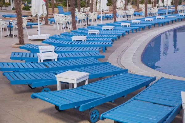 Lettini lounge vicino alla piscina.Sdraio a bordo piscina, atmosfera blu e confortevole.Lettini a bordo piscina nella natura. Lettini vuoti vicino alla bella piscina del resort  . — Foto Stock