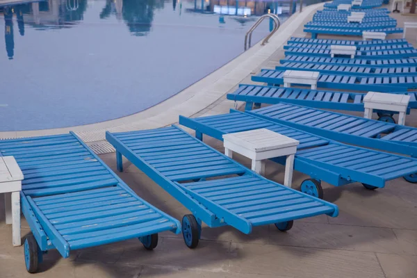 Lettini lounge vicino alla piscina.Sdraio a bordo piscina, atmosfera blu e confortevole.Lettini a bordo piscina nella natura. Lettini vuoti vicino alla bella piscina del resort  . — Foto Stock