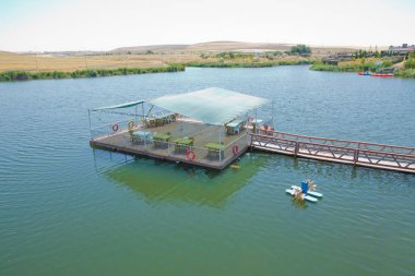 Dağ sırasının önündeki bir dağ gölünün manzarası. Muhteşem göl manzarası. Mavi ve yeşilin işbirliği. Gölün ortasında restoran ve köprü . Abant Gölü Golu Manzarası .