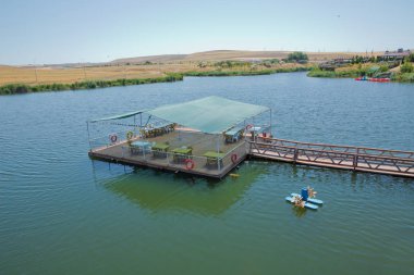 Dağ sırasının önündeki bir dağ gölünün manzarası. Muhteşem göl manzarası. Mavi ve yeşilin işbirliği. Gölün ortasında restoran ve köprü . Abant Gölü Golu Manzarası .