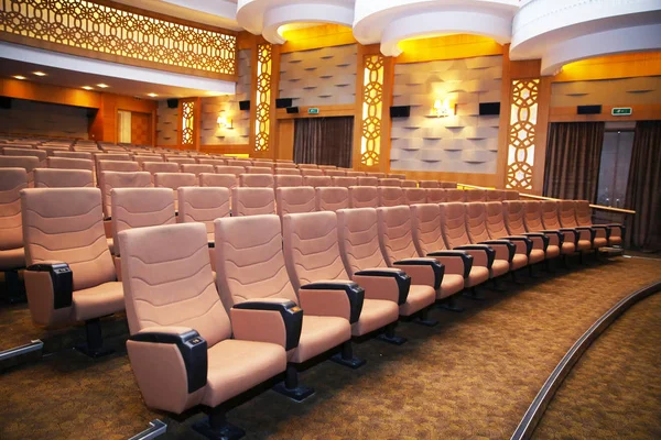 Wood armed formal plush deep red velvet opera movie theater chairs in curved row with decorative gold molding in fancy carpeted venue — Stock Photo, Image