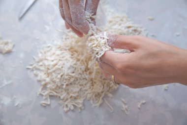 Makarna pişirmek için uzun hamur şerit kesme. Ev yapımı gıda hazırlama konsepti. Ev yapımı makarna pişirme sürecinin yakın çekim. Erişte . Genç ev karısı mutfakta ev yapımı makarna hazırlanıyor.