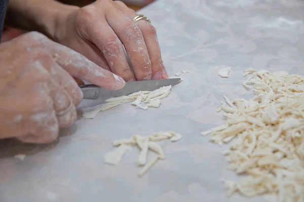 Cutting long dough stripe for cooking pasta. Homemade food preparation concept. Closeup of process of making cooking homemade pasta. Erishte . Young house wife preparing the homemade pasta at kitchen. — Stock Photo, Image