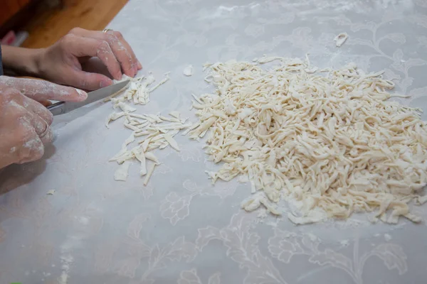 Cutting long dough stripe for cooking pasta. Homemade food preparation concept. Closeup of process of making cooking homemade pasta. Erishte . Young house wife preparing the homemade pasta at kitchen. — Stock Photo, Image
