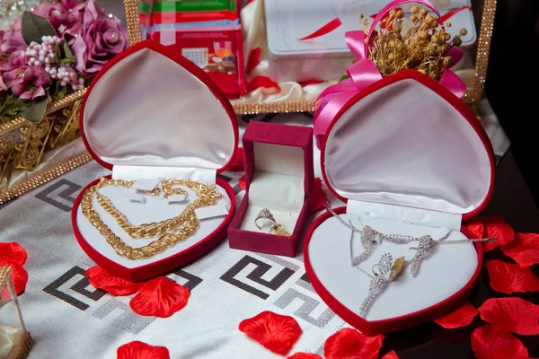 Colar de ouro em uma caixa vermelha na forma de um heaart. Colar de ouro e anéis de orelha e jóias de prata com pérolas sendo colocadas e exibidas em caixa com veludo vermelho para ser dado como um presente para a noiva  . — Fotografia de Stock