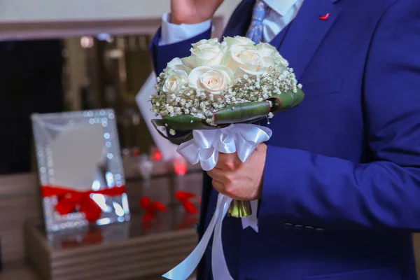 ブーケとスタイリッシュなエレガントな幸せな新郎。手に結婚式の花束を持つスタイリッシュな自信に満ちた美しい若い花嫁。朝の新郎の結婚式の料金 . — ストック写真