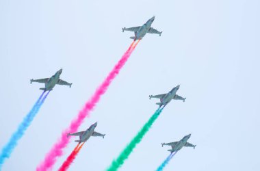 Bir grup Rus askeri savaş uçağının mavi gökyüzünde yüksekten uçarak geçit töreni hava gösterisi sırasında mavi beyaz kırmızı duman izi bırakması .