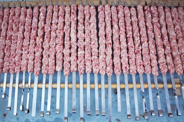 Lula kebab na špejlích, tradiční kavkazské jídlo, zblízka. Apetizující Lulu kebab na kovové špíze. Vaření masa. — Stock fotografie