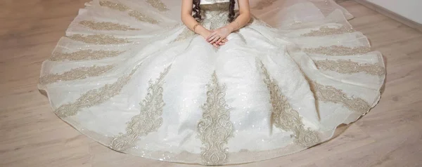 Ritratto a colori di bella sposa in abito da sposa bianco seduto sul pavimento catturato. La sposa si mette la mano sul braccio. Bellezza sposa in abito bianco posti a sedere sul pavimento  . — Foto Stock