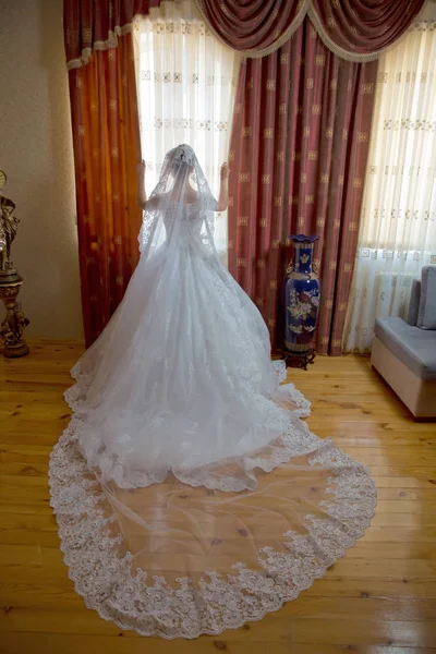 Braut in Weiß Hochzeit. schöne Braut im weißen Hochzeitskleid steht in ihrem Schlafzimmer am Fenster . — Stockfoto