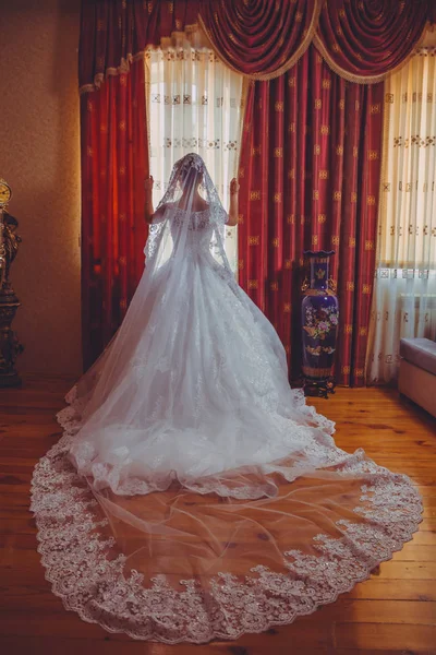 Noiva em casamento branco. Bela noiva em vestido de noiva branco de pé em seu quarto perto da janela  . — Fotografia de Stock