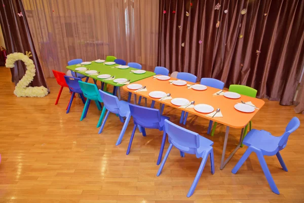 Детская мебель и игрушки в детском саду. детский сад класс с зелеными стульями и столиками. Детская столовая в детском саду  . — стоковое фото