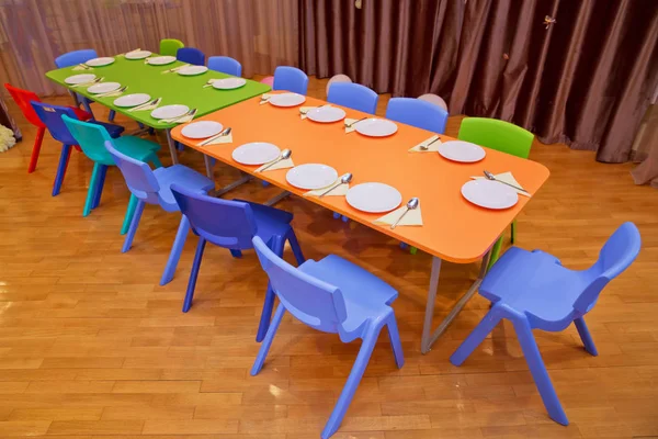 Детская мебель и игрушки в детском саду. детский сад класс с зелеными стульями и столиками. Детская столовая в детском саду  . — стоковое фото