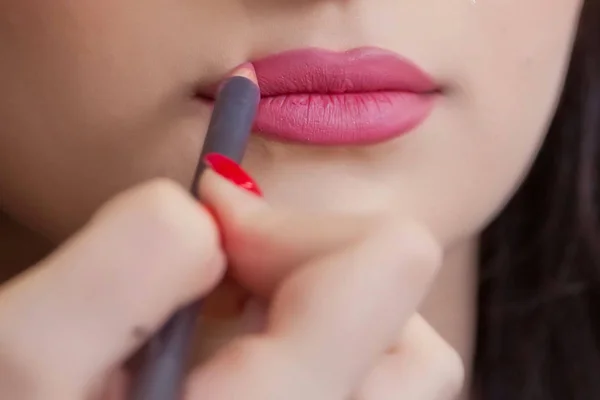 Tangan wanita dari visagiste memegang pensil dan menggambar bibir. Seniman Makeup profesional menerapkan pensil lipstik pengantin. Menutup gadis cantik tak dikenal mendapatkan bibirnya dicat . — Stok Foto