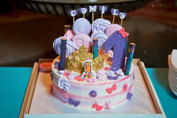 Delicioso pastel de arco iris en el plato en la mesa. Escritura de 1 año. hecho en casa decorar pastel crema de mantequilla rosa alrededor de la torta. Pastel de arco iris rosa  . — Foto de Stock