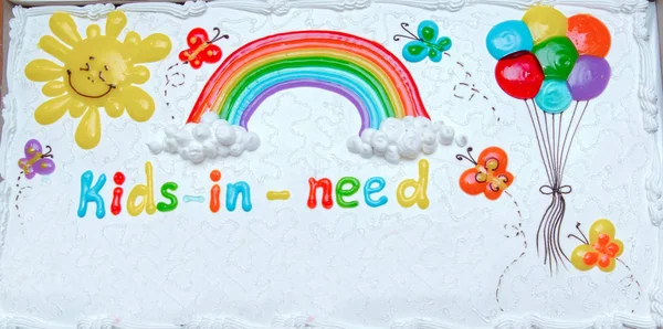 Cake kids-in-need is written . Balloon and the sun . Rainbow cake with colorful candles . White Rainbow cake .