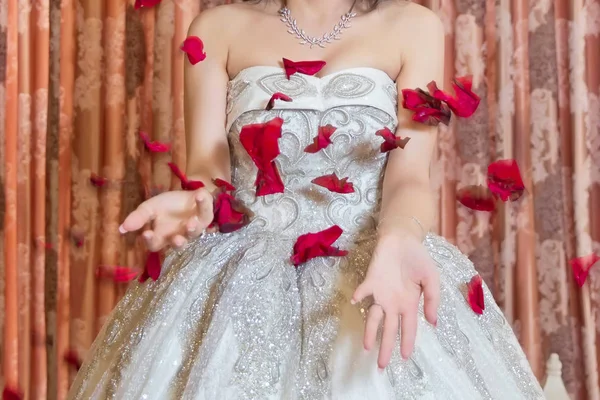 Τα πέταλα των κόκκινων τριαντάφυλλων πέφτουν στην ευτυχισμένη νύφη. Η νύφη ρίχνει κόκκινα πέταλα . — Φωτογραφία Αρχείου