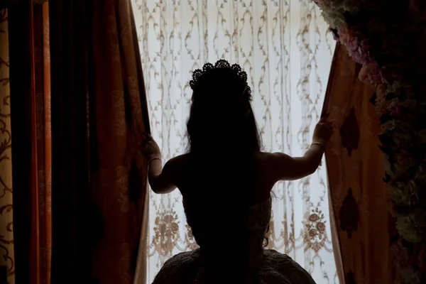 Gelin, gelinliğin arkasını gösteren balayı süitinin büyük penceresinden dışarı bakar. Beyaz bir düğünün arka tarafı, elbisesinde bir kalp taşır..